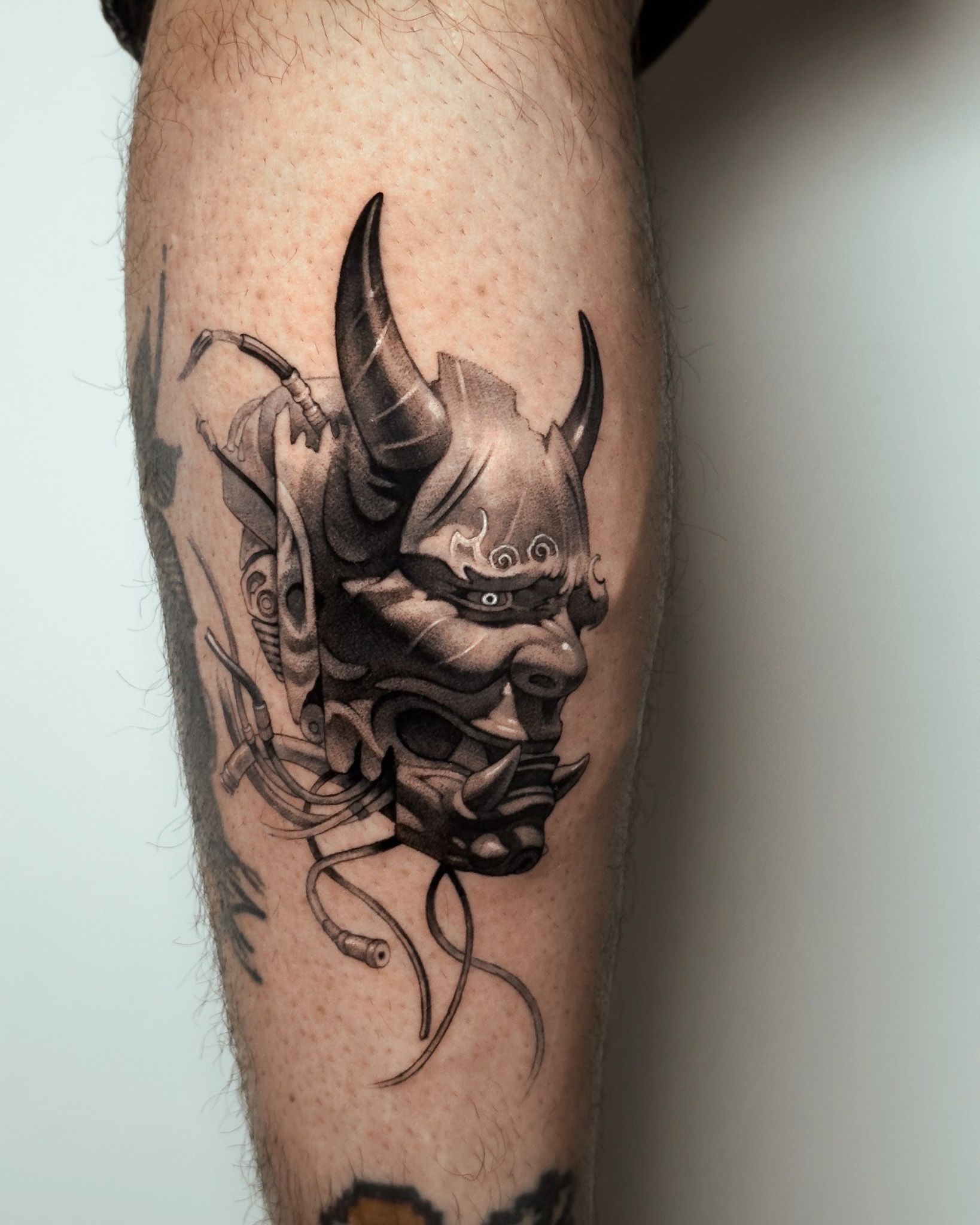 Detailed black and grey Japanese oni mask tattoo on forearm