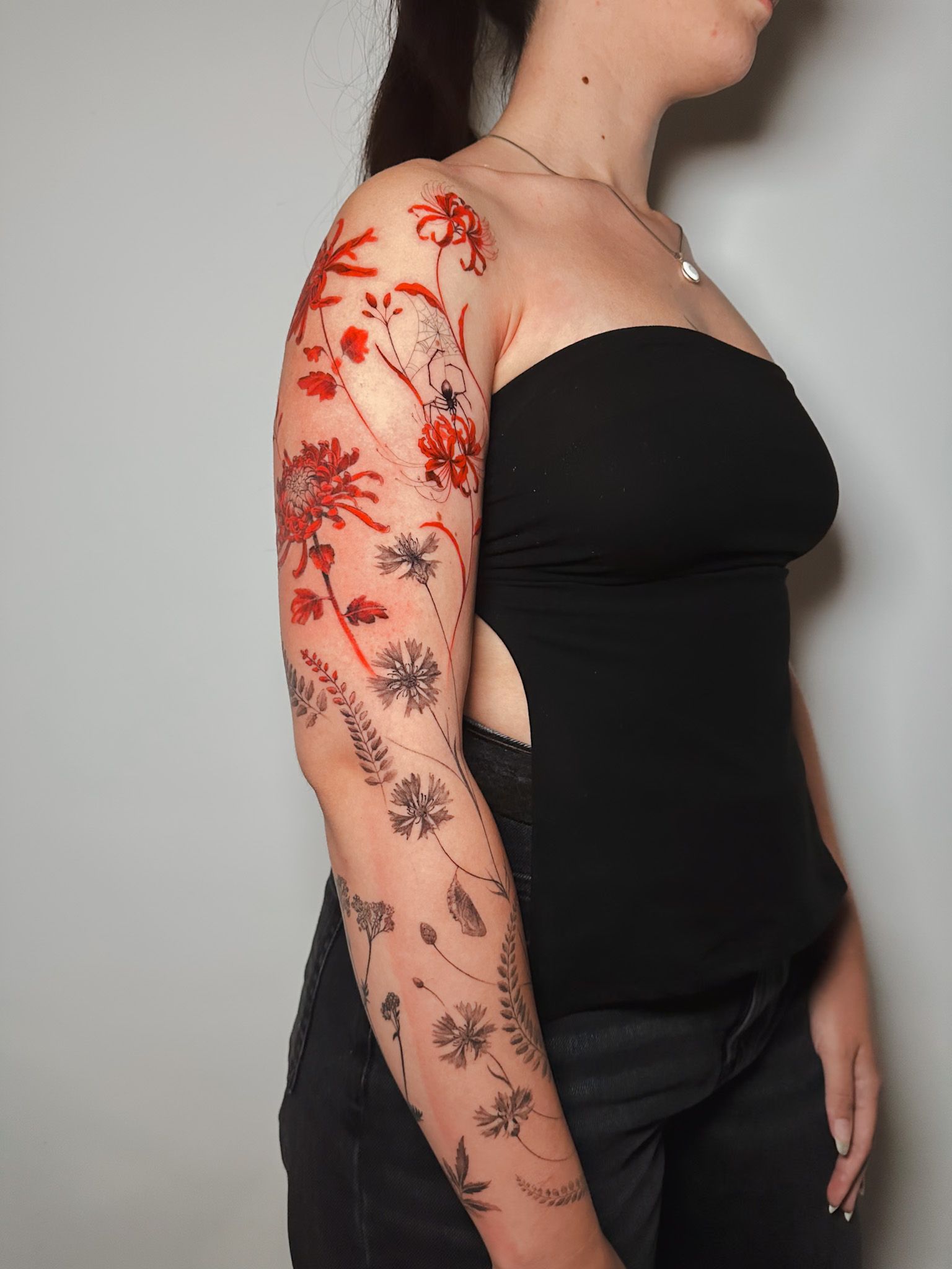 Realistic red and black floral sleeve tattoo on upper arm